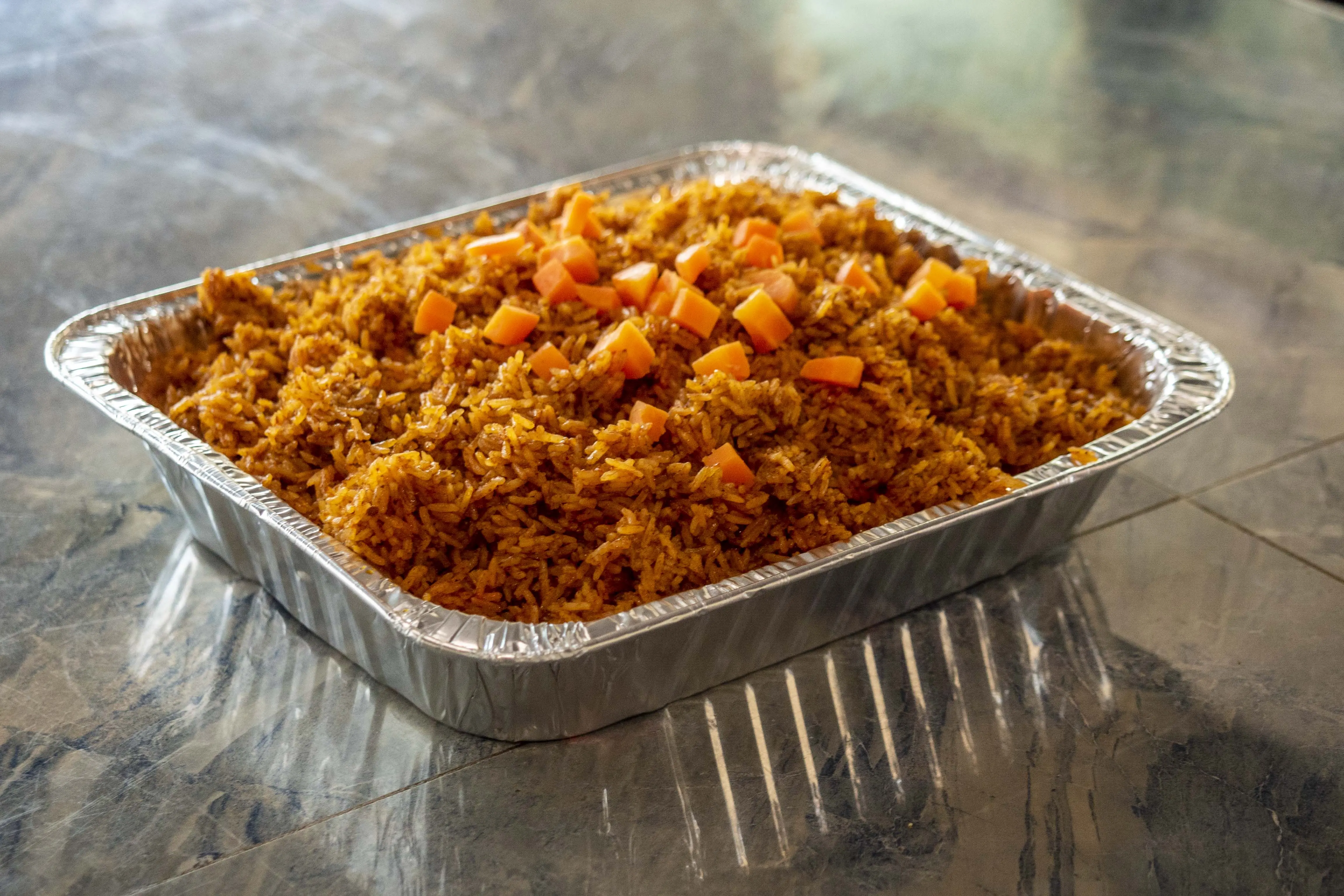 Large party-size jollof rice catering tray for events — Diamonds & Pearls Catering