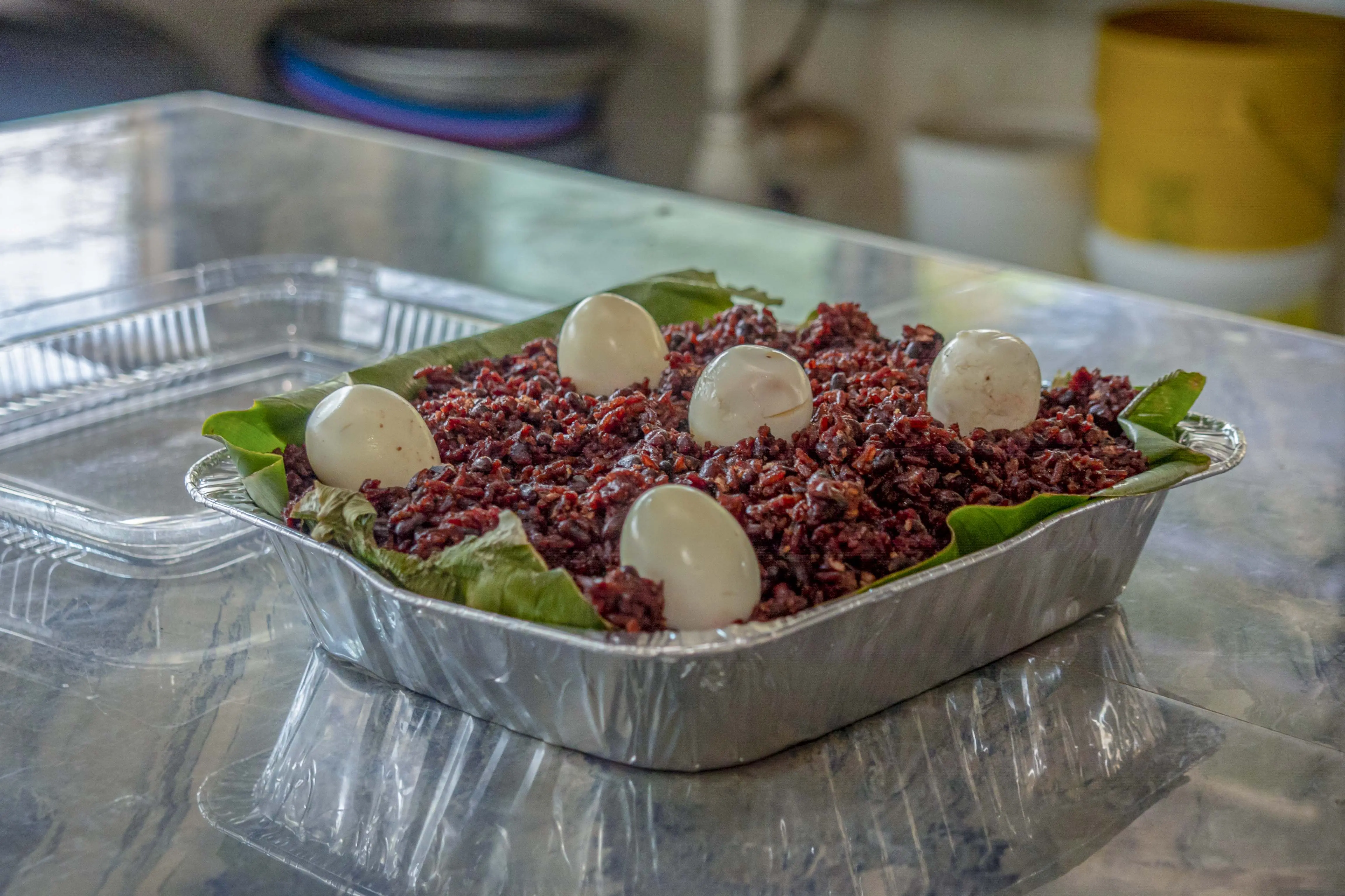 Large tray of waakye with boiled eggs served on plantain leaves — Ghanaian catering